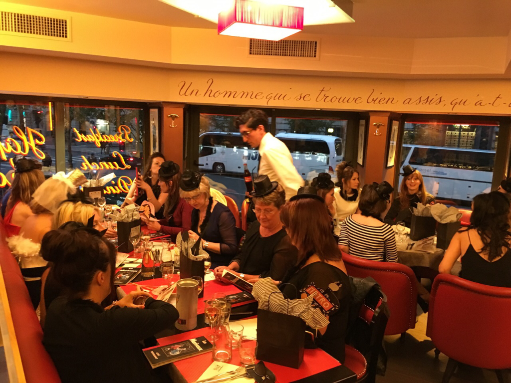 Salle de restaurant conviviale avec clients autour de tables rouges, ambiance chaleureuse et festive