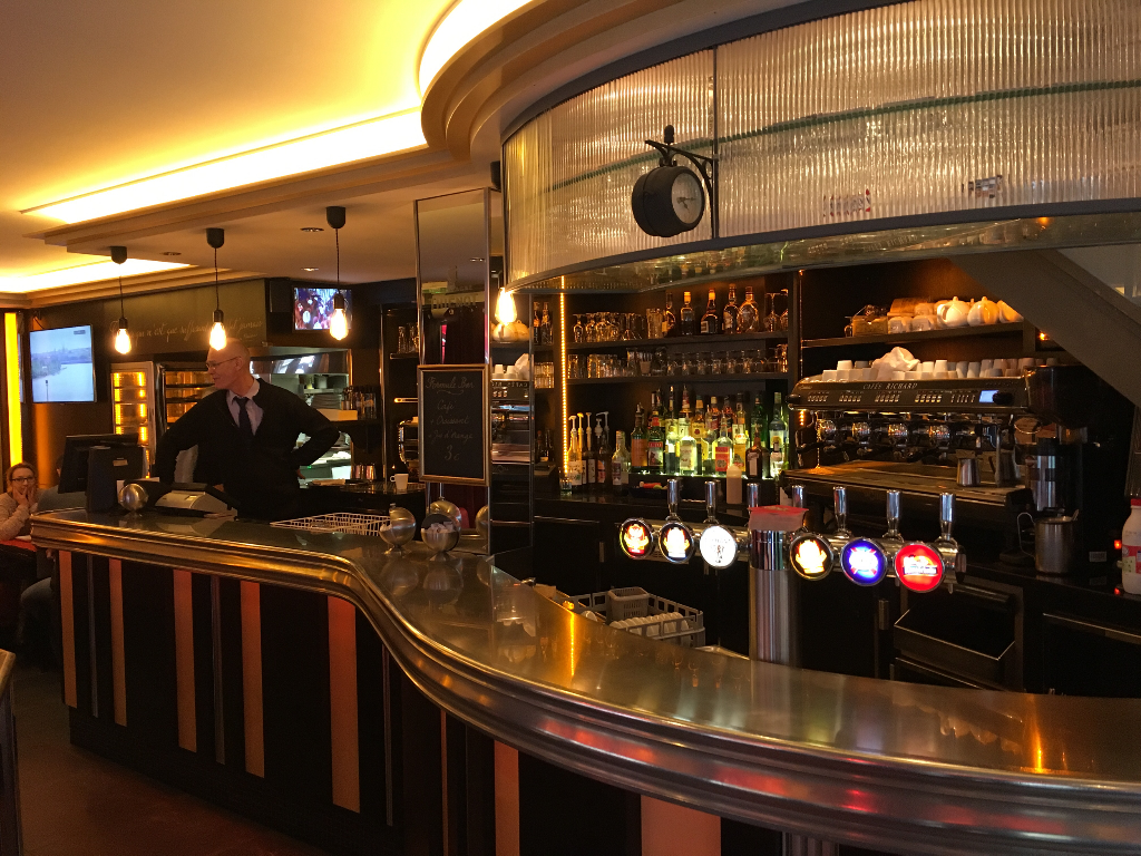 Bar lounge élégant avec comptoir courbe, poutres dorées et éclairage chaleureux