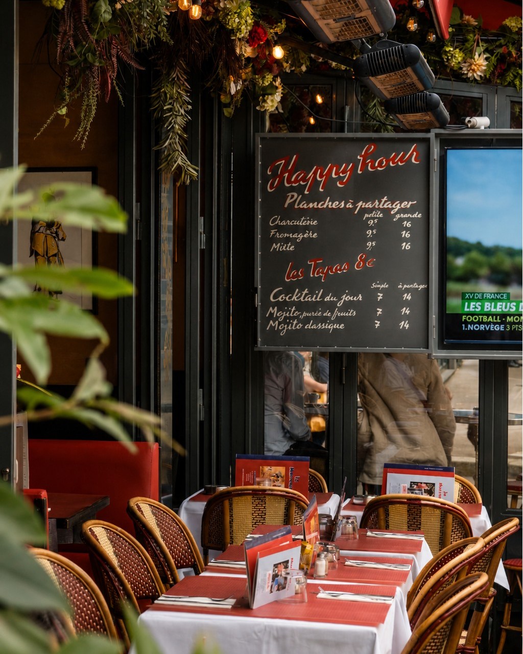 Terrasse parisienne du Marivaux avec chaises en rotin, menu Happy Hour et ambiance estivale