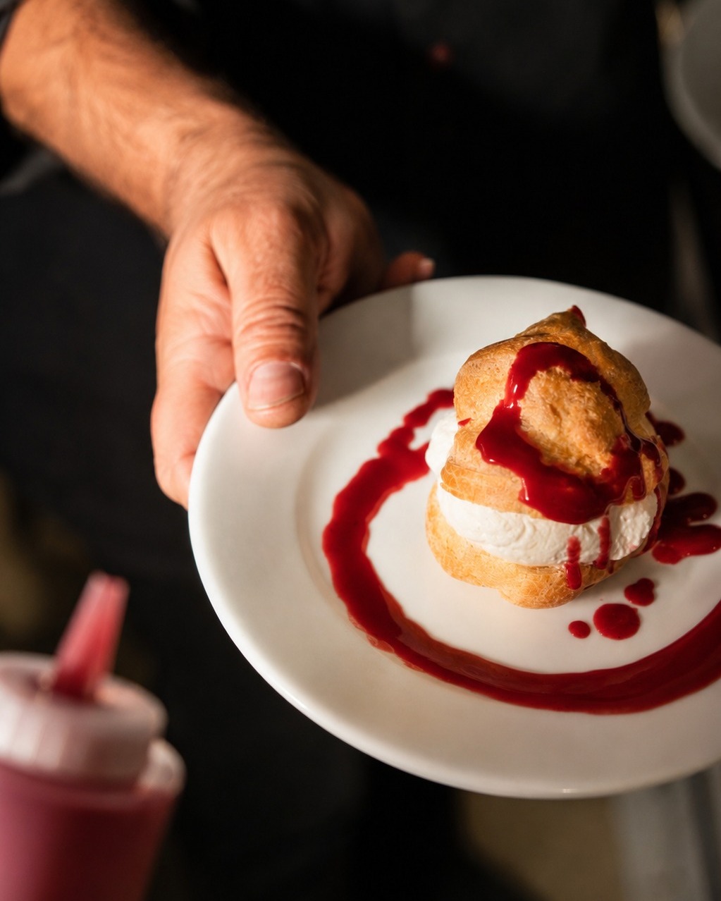 Dessert gastronomique : religieuse aux fruits rouges, crème et coulis