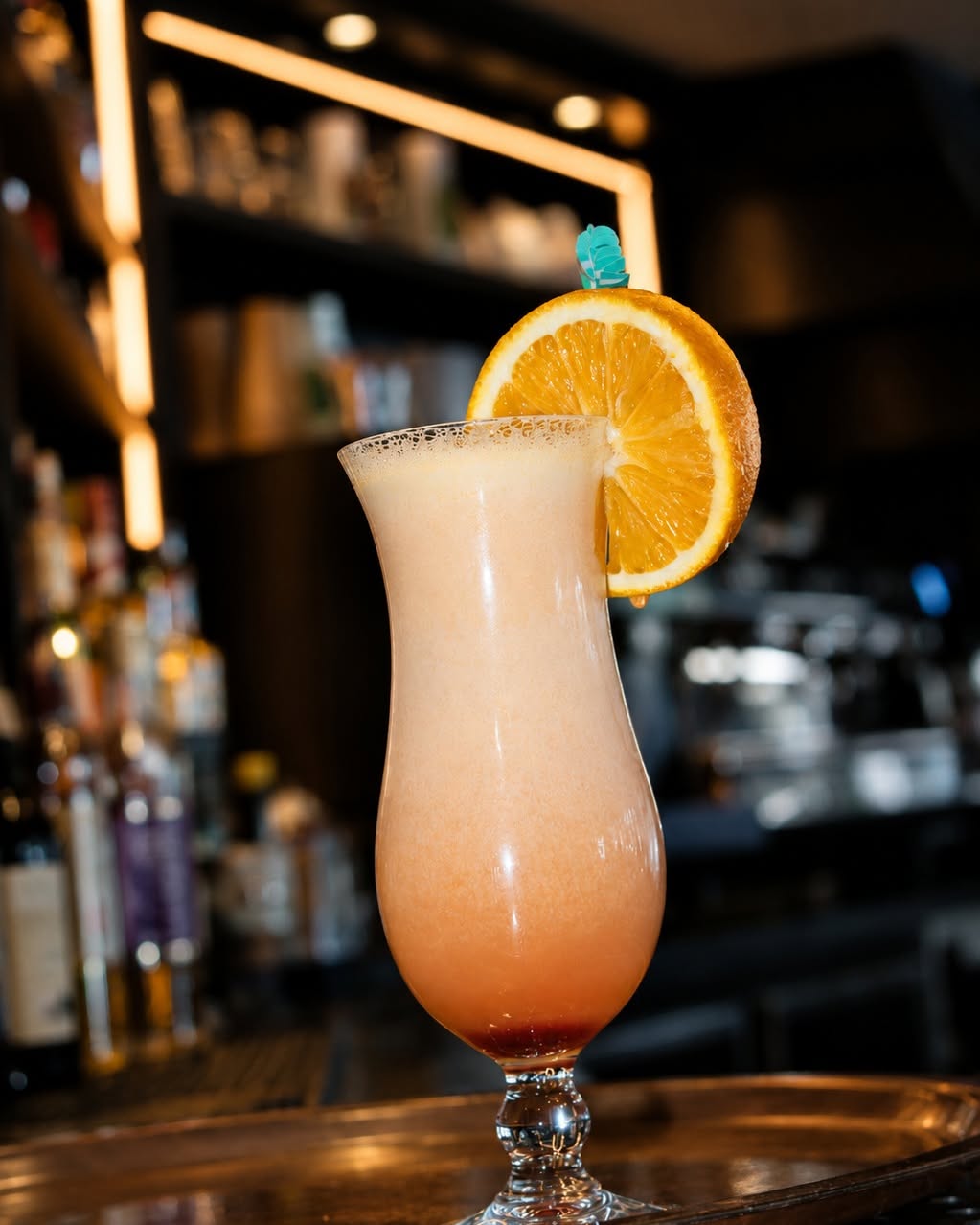 Cocktail sunset dégradé orange et blanc avec glaçon et tranche d'orange