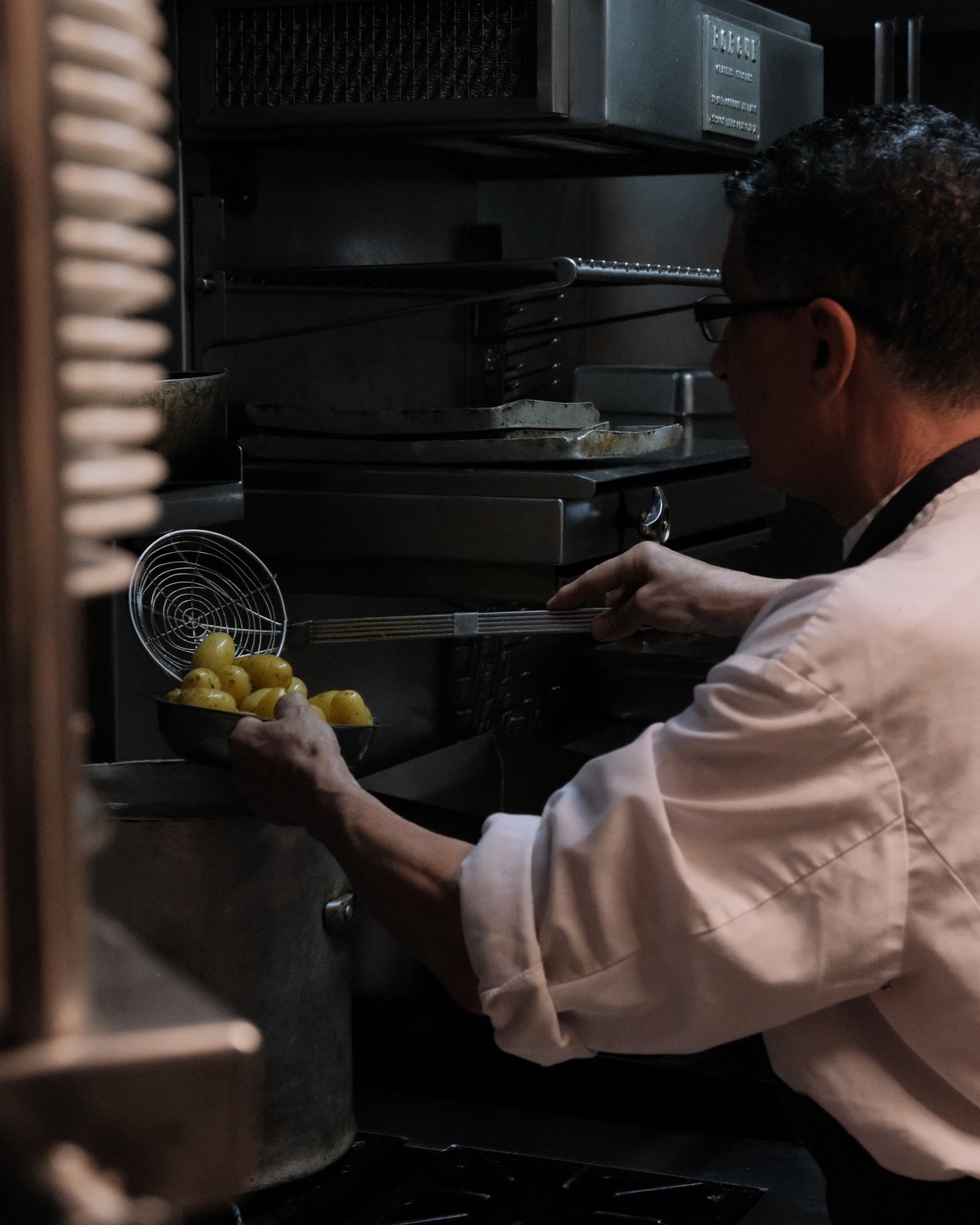 Chef en cuisine préparant des pommes de terre à l'oven, restaurant Marivaux