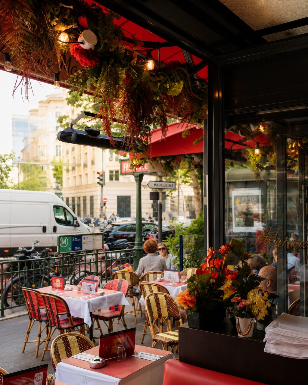 Terrasse parisienne avec chaises bistrot rouge et or, fleurs suspendues, ambiance chaleureux
