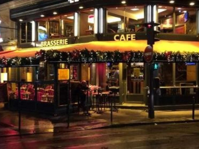 Façade illuminée d'une brasserie-café la nuit avec décoration festive