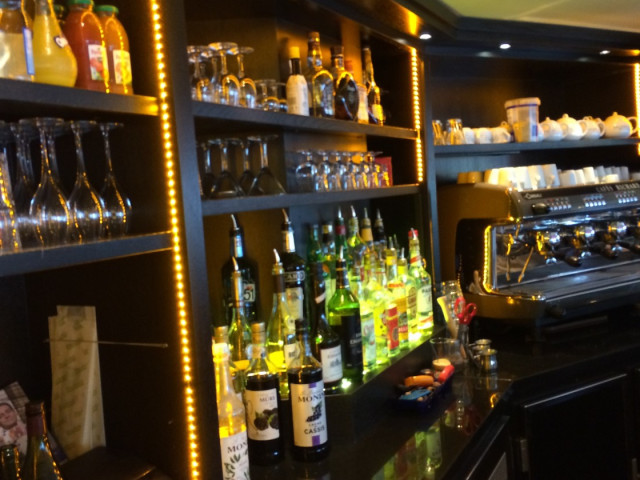 Bar moderne avec étagères illuminées, verres et bouteilles de vin et spiritueux