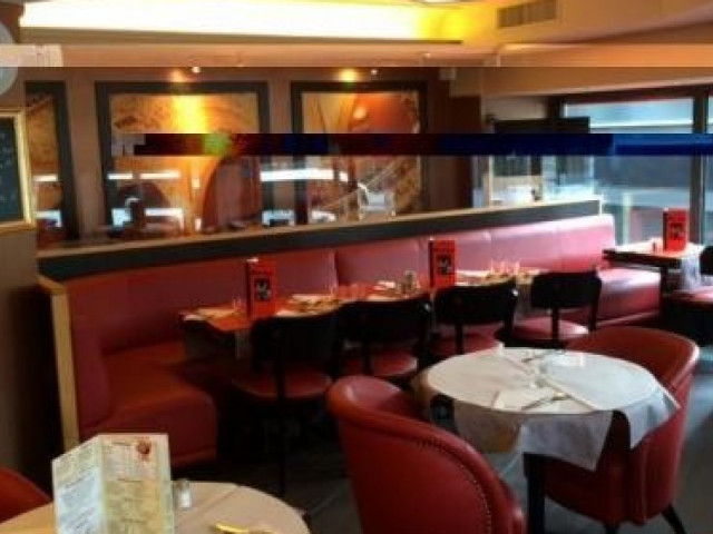 Salle de restaurant avec banquettes rouges et tables en bois