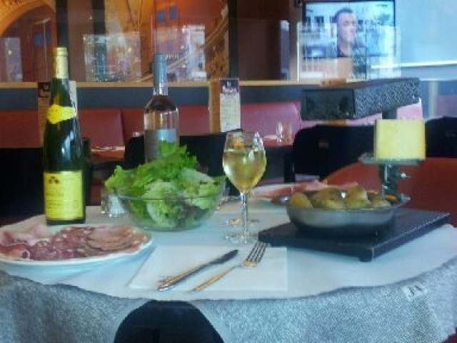 Table dressée avec charcuterie, salade verte et verre de vin blanc dans restaurant