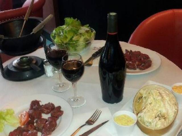 Table de restaurant avec charcuterie, salade verte et verre de vin rouge